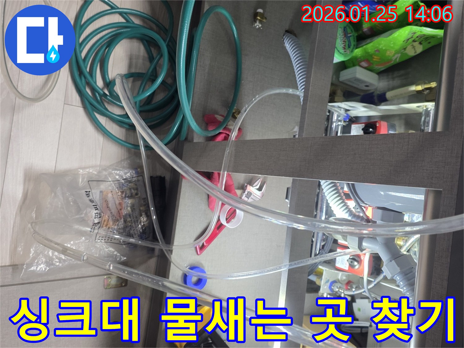 싱크대 아래에서 물이 새는 곳을 정확히 찾아내기 위해-다양한 탐지 장비와 호스를 활용하여-면밀하게 점검하고 있는 현장입니다.