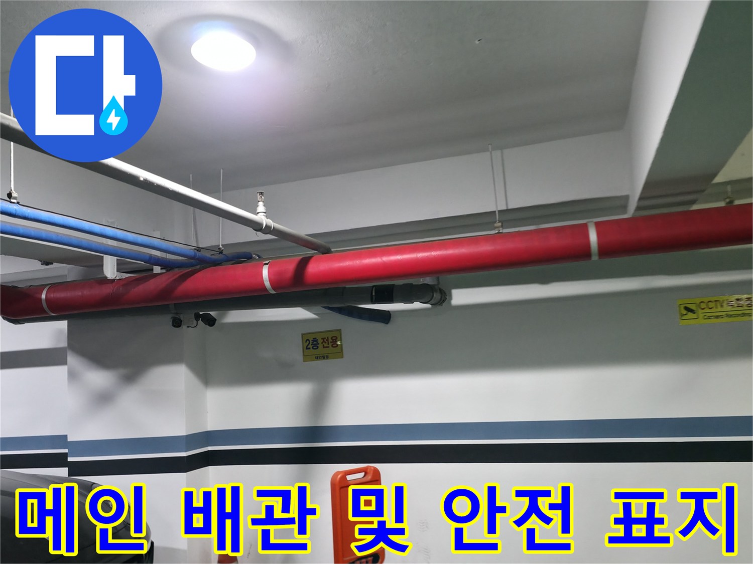 천장에 설치된 붉은색과 파란색의 큰 관들과 경고 스티커