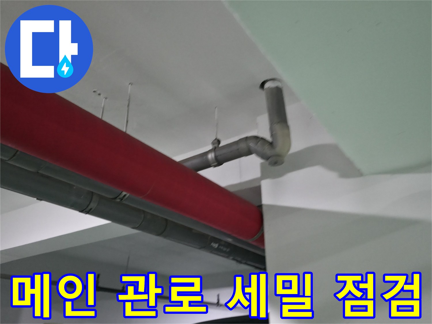 회색 배관과 붉은색 마감재가 대조되는 천장 내부 구조