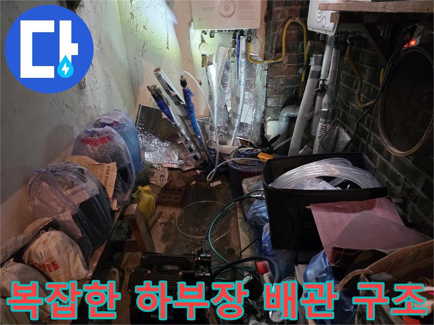 주방 싱크대 아래 얽힌 배관들과 작업용 도구들