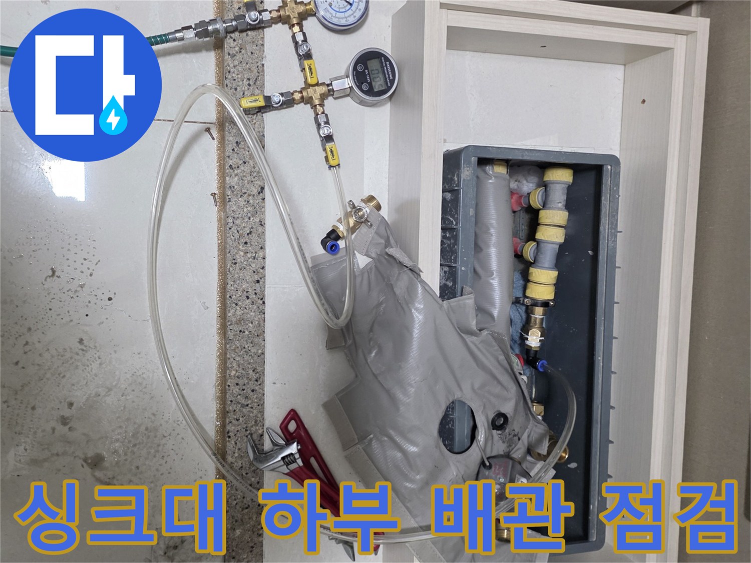 싱크대 하단 분배기에 연결된 압력 측정 게이지와 호스들