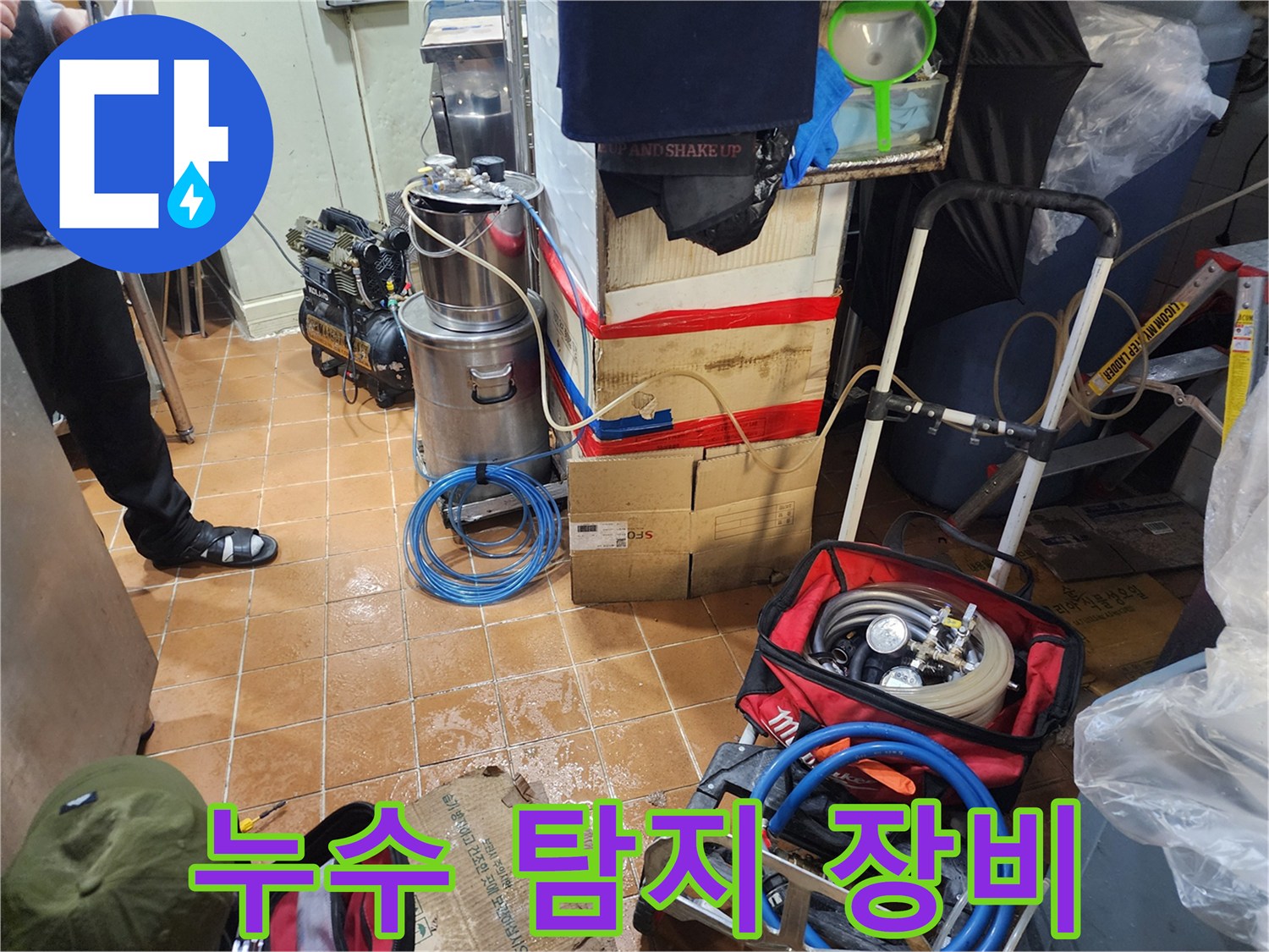 바닥에 놓인 압력 테스트용 펌프와 파란색 호스 - 현장 작업 모습