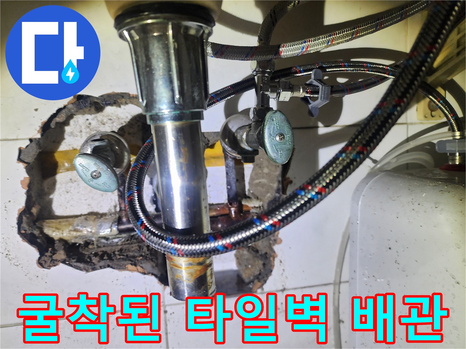타일이 제거된 벽면 내부의 노출된 금속 배관과 연결 소모품들