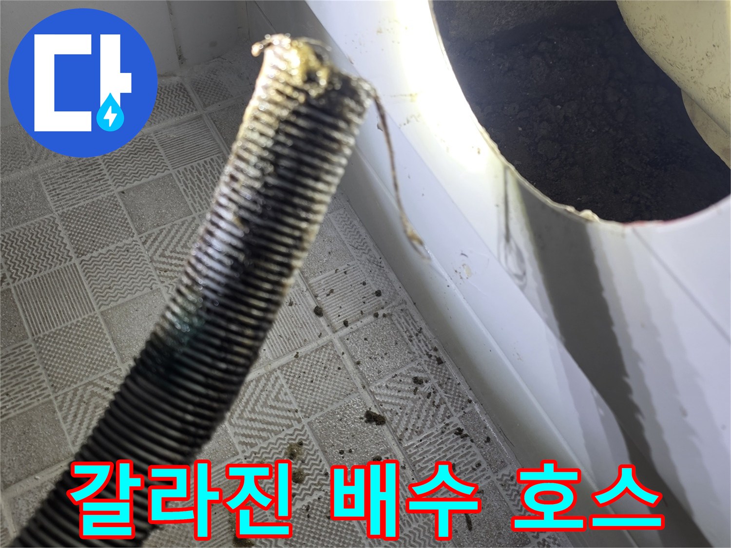 욕조 하부 점검창 너머로 보이는-찢어진 배수 호스의 균열 부위입니다.