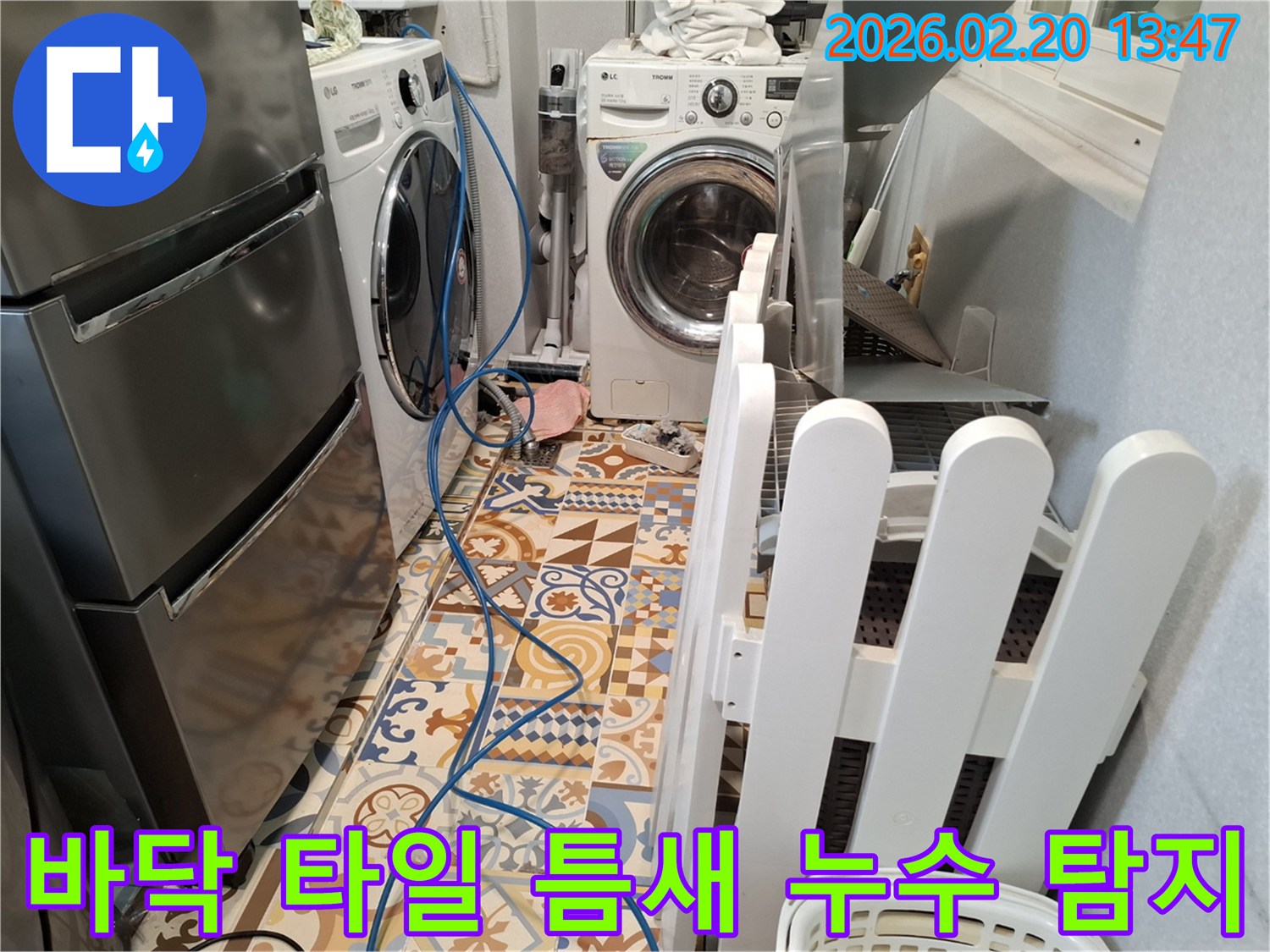 빌라 세탁실 바닥에 누수 탐지 장비 호스가 설치되어 있고-타일 틈새 누수를 정밀하게 탐지하는 현장입니다.