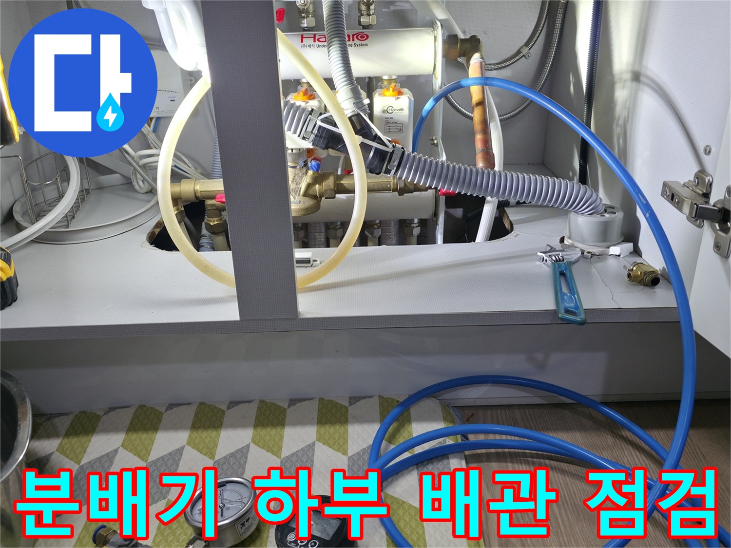 싱크대 아래 분배기 밸브와 압력 측정 장비가 설치된 작업 장면