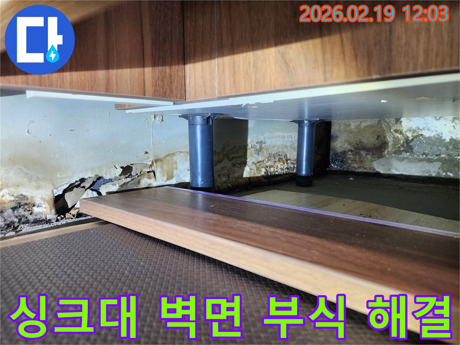 싱크대 하부 벽면의 심각한 누수 흔적-벽지 손상과 곰팡이가 광범위하게 퍼진 상태를 전문가가 진단