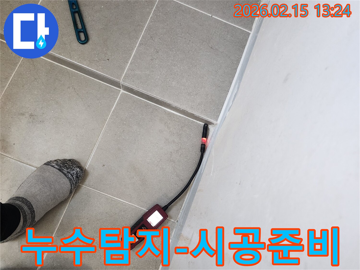 누수 엔지니어가 바닥 타일과 벽면 경계에서 누수탐지기를 사용하여 공사 전 정밀 진단을 하는 모습