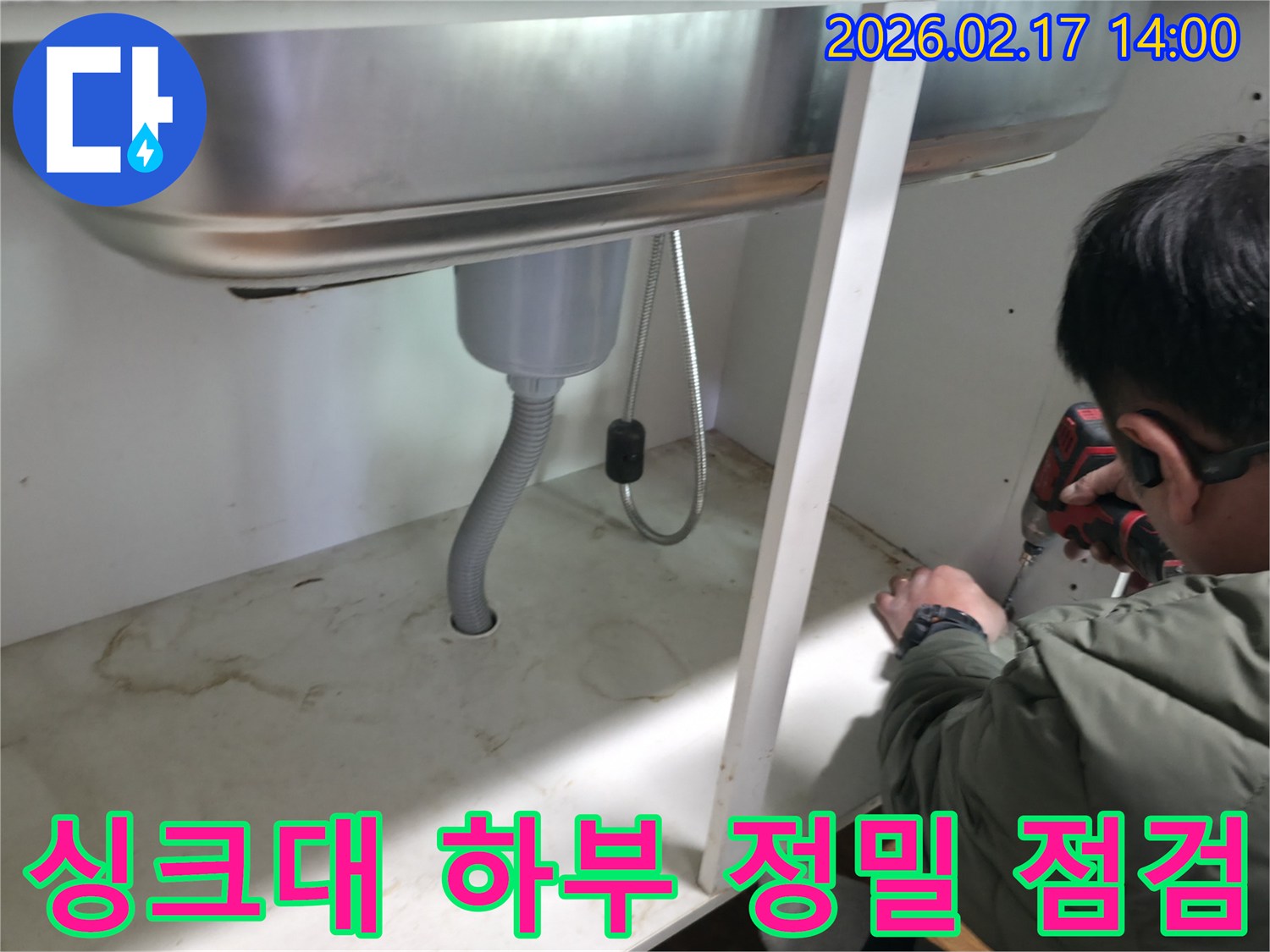 싱크대 하부의 배관과 연결 부위를-전문가가 면밀하게 정밀 점검하는 모습
