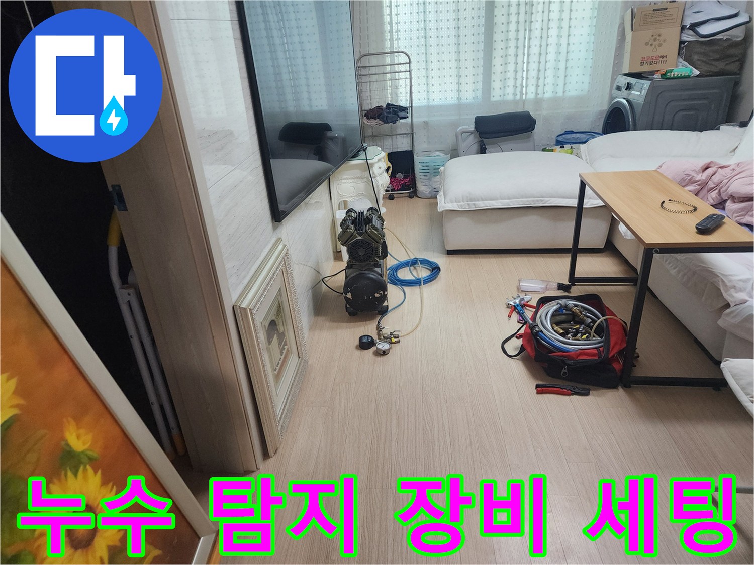 거실 바닥에 배치된 누수 점검용 콤프레샤와 연결 호스들