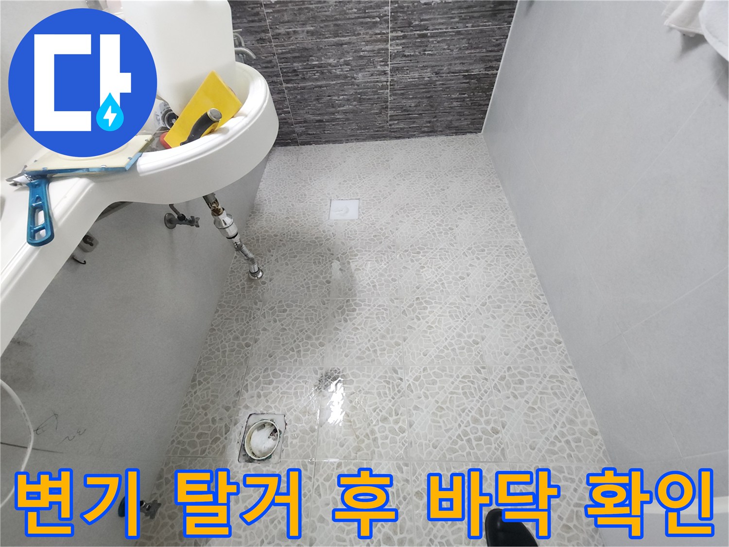 변기를 제거한 후 드러난 하얀 타일 바닥의 유가 및 배관 부위