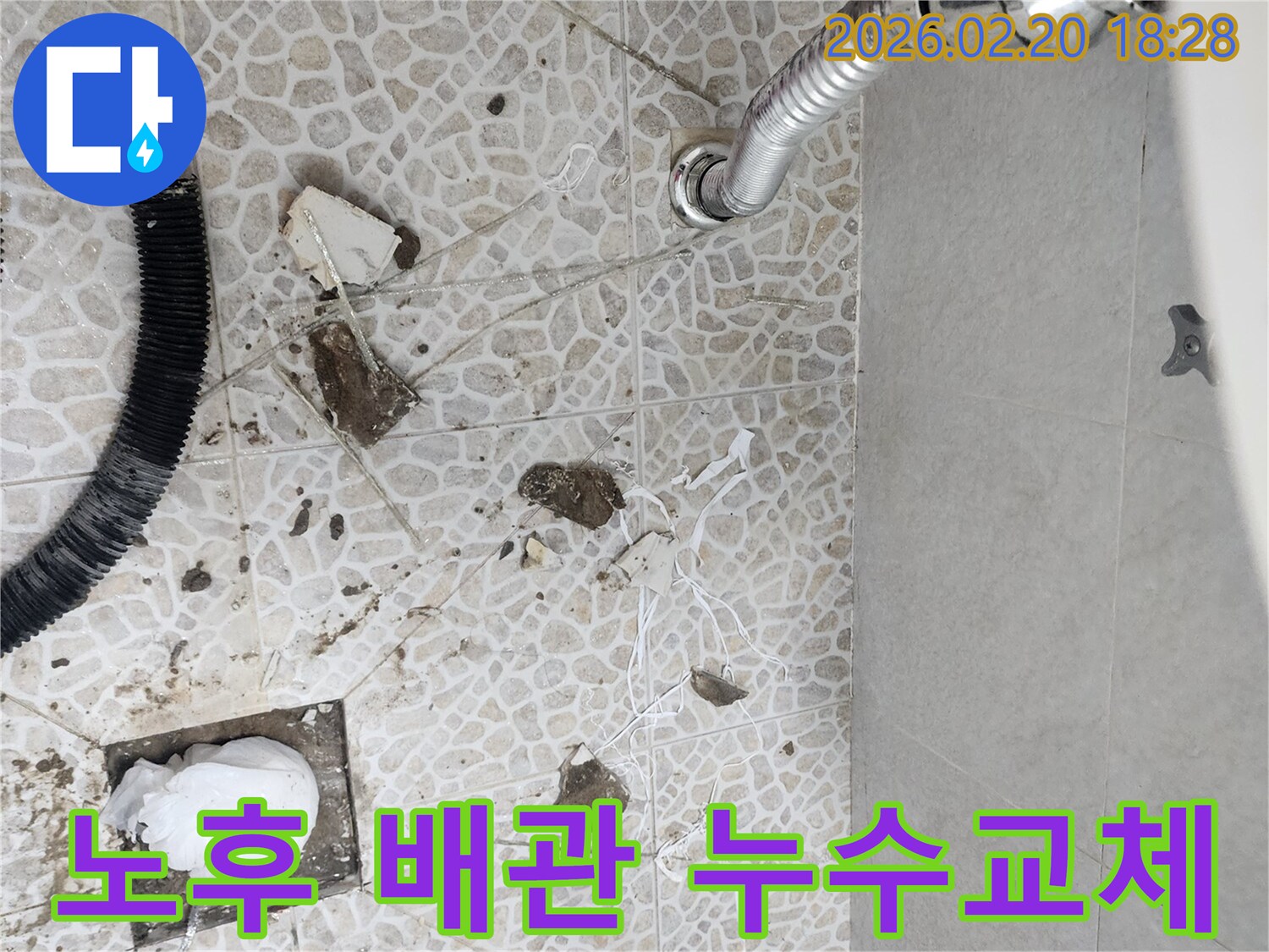 이 이미지는 서울 동대문구의 한 건물에서 발생한 노후 배관 누수를 해결하기 위해-전문가가 바닥을 파쇄하고-손상된 배관을 교체하는 공사 현장을 보여줍니다.