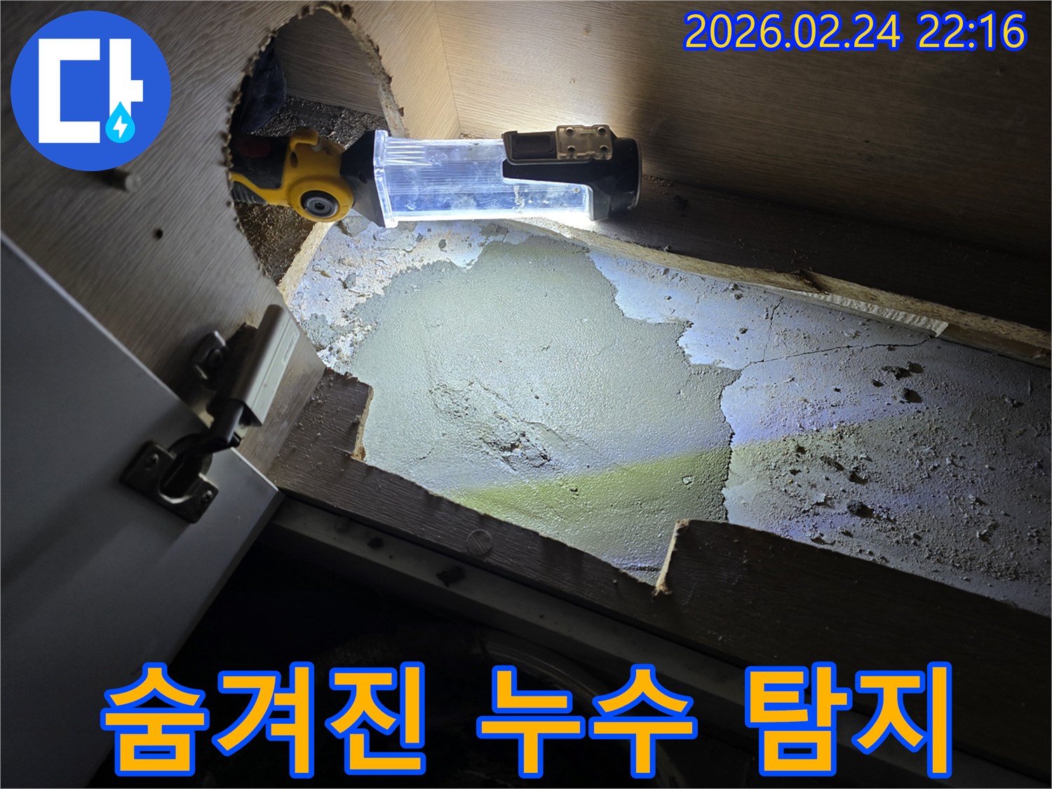 누수-엔지니어가-어두운-싱크대-하부에서-숨겨진-누수-지점을-찾기-위해-조명-장비를-사용하여-정밀-탐지하는-모습