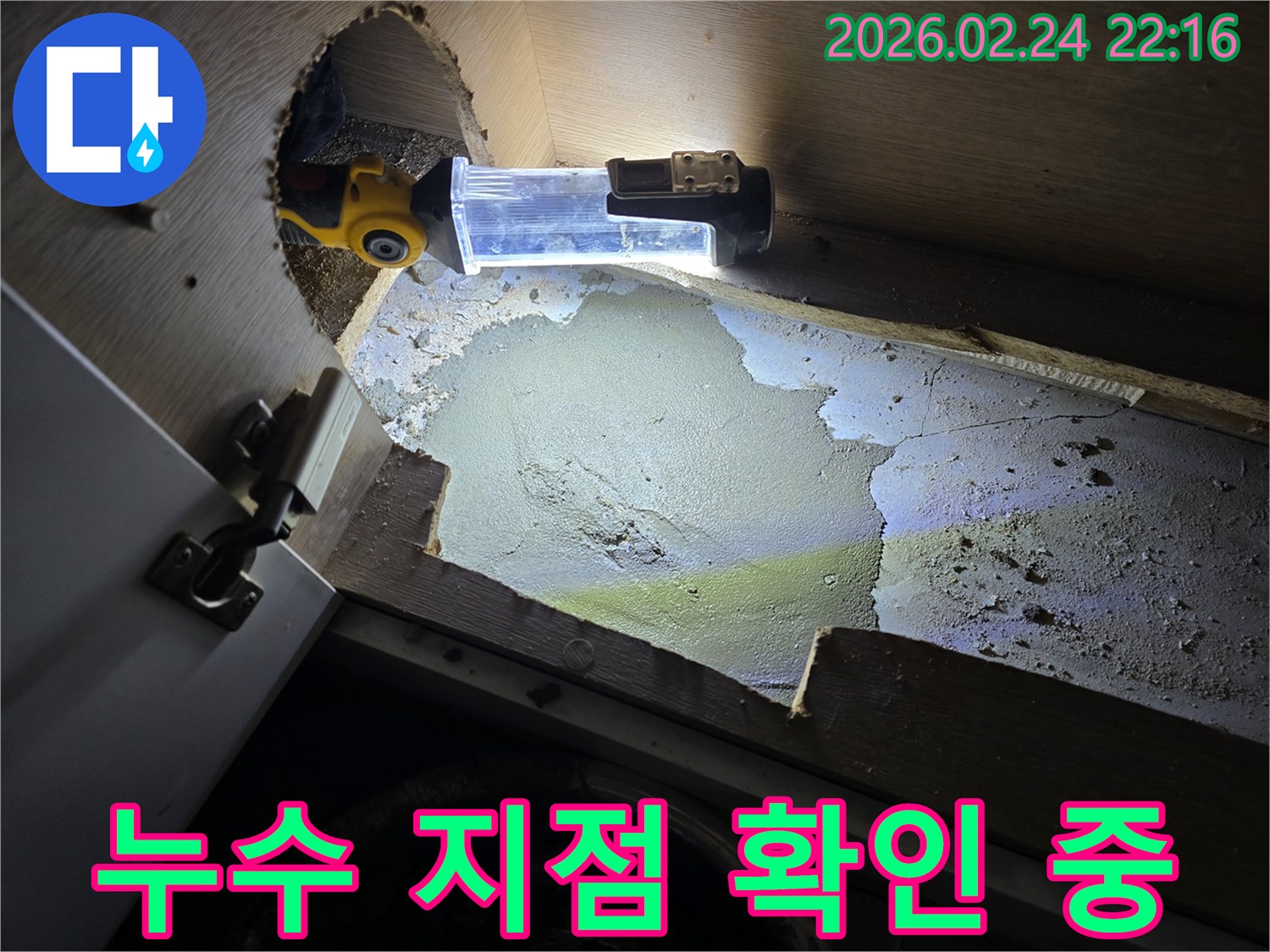 누수-엔지니어가-어둡고-좁은-싱크대-하부에서-누수-지점을-확인하기-위해-조명-장비를-사용하여-탐지하는-모습