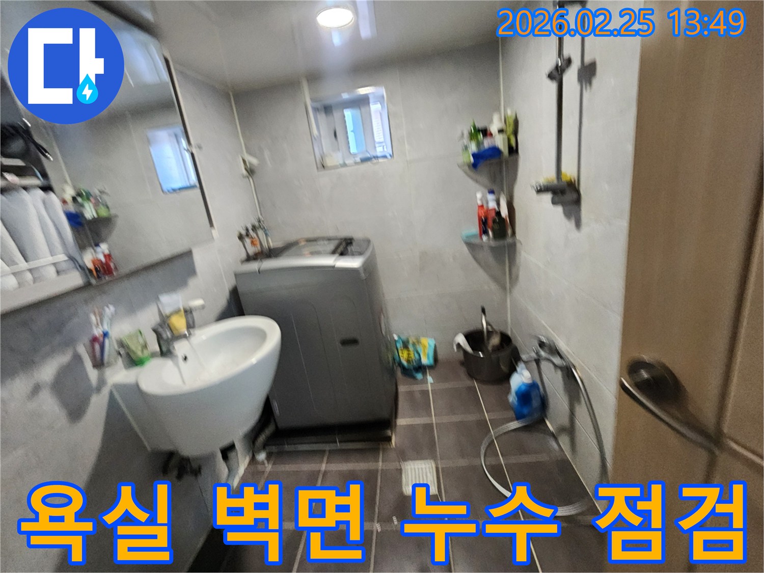 세탁기와-세면대가-있는-욕실에서-벽면-누수-여부를-확인하기-위해-현장을-점검하는-사진