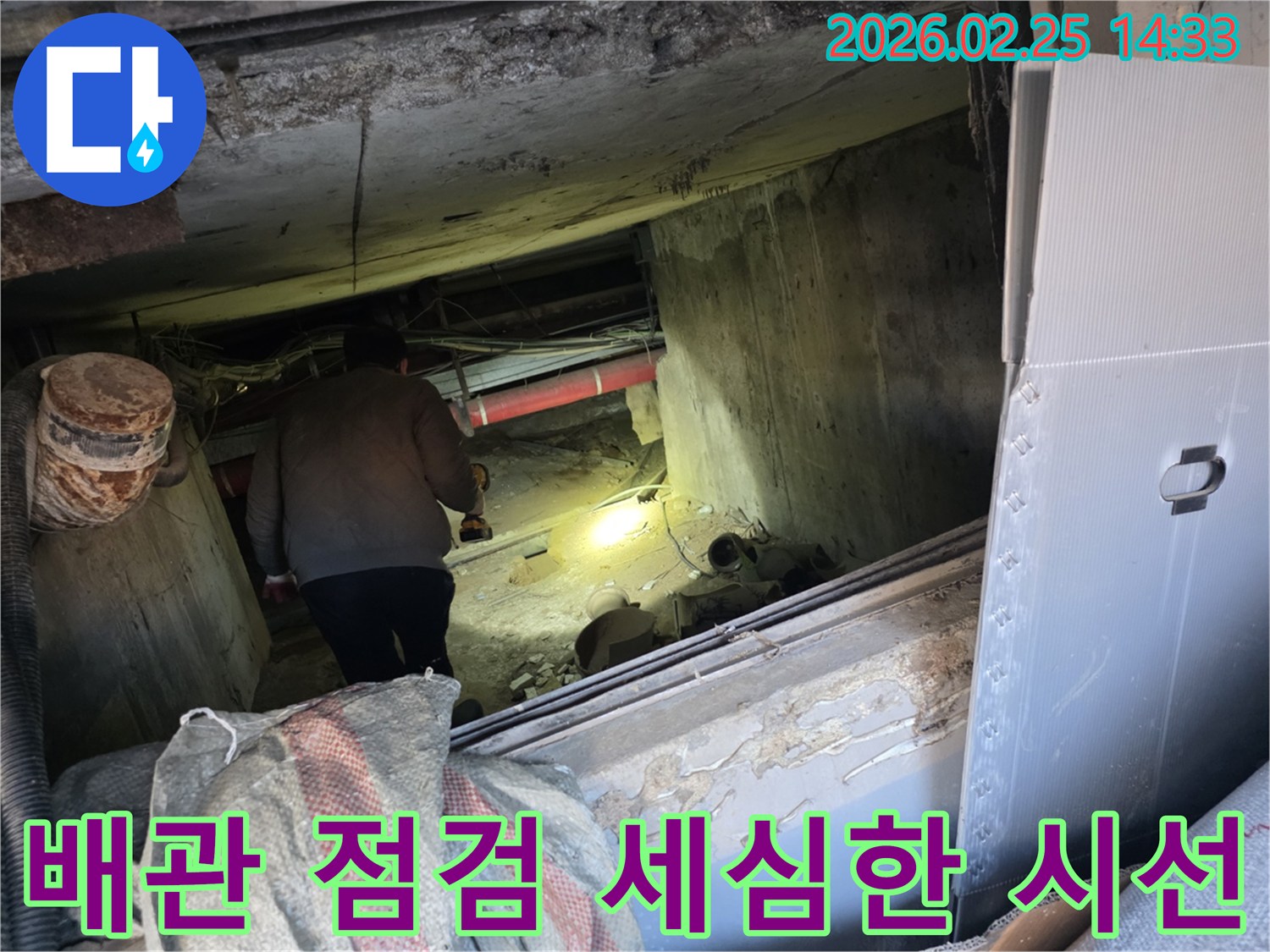 누수 전문 엔지니어가-어둡고 좁은 공간에서-손전등을 비춰가며-배관의 미세한 문제까지-세심하게 점검하는 모습입니다.