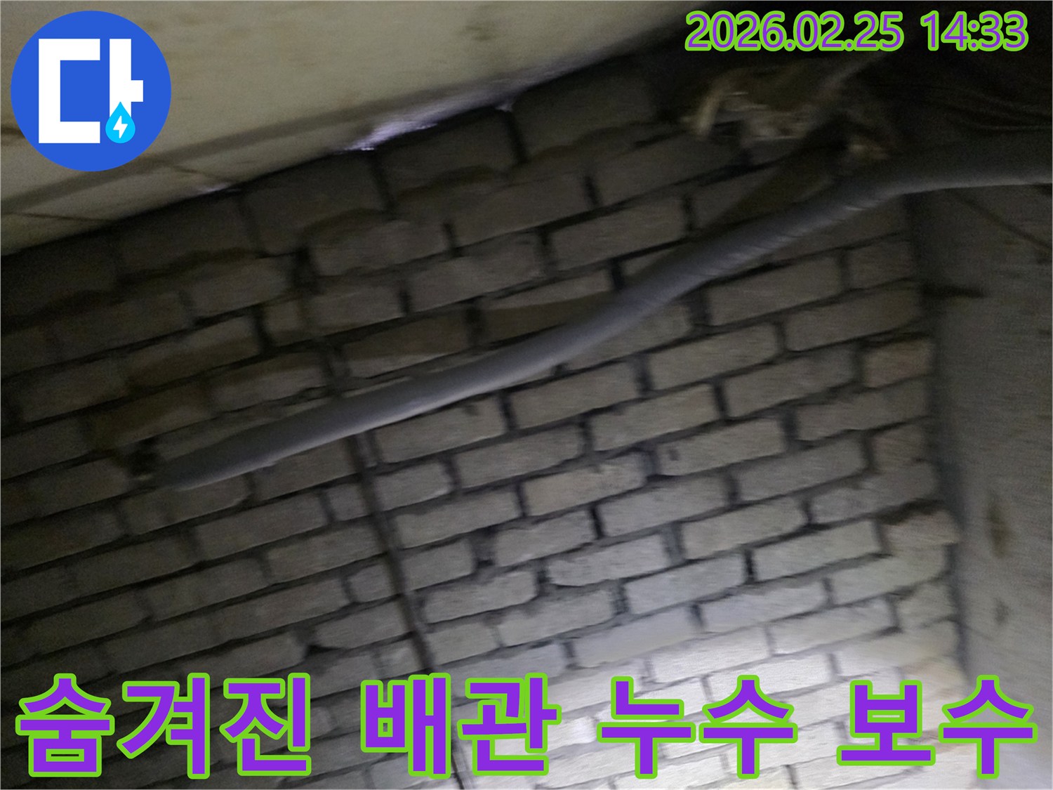 어두운 벽돌 벽면을 배경으로-단열된 배관과 함께-숨겨진 누수 지점을 보수하기 위해-정밀하게 검사되는 현장 모습입니다.