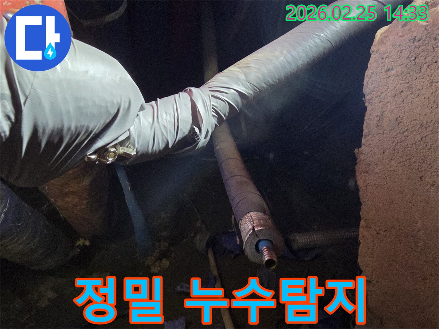 어두운 작업 공간에서-장갑을 낀 손이-첨단 장비를 활용하여-배관의 미세한 누수 지점을-정확하게 탐지하고-확인하는 모습입니다