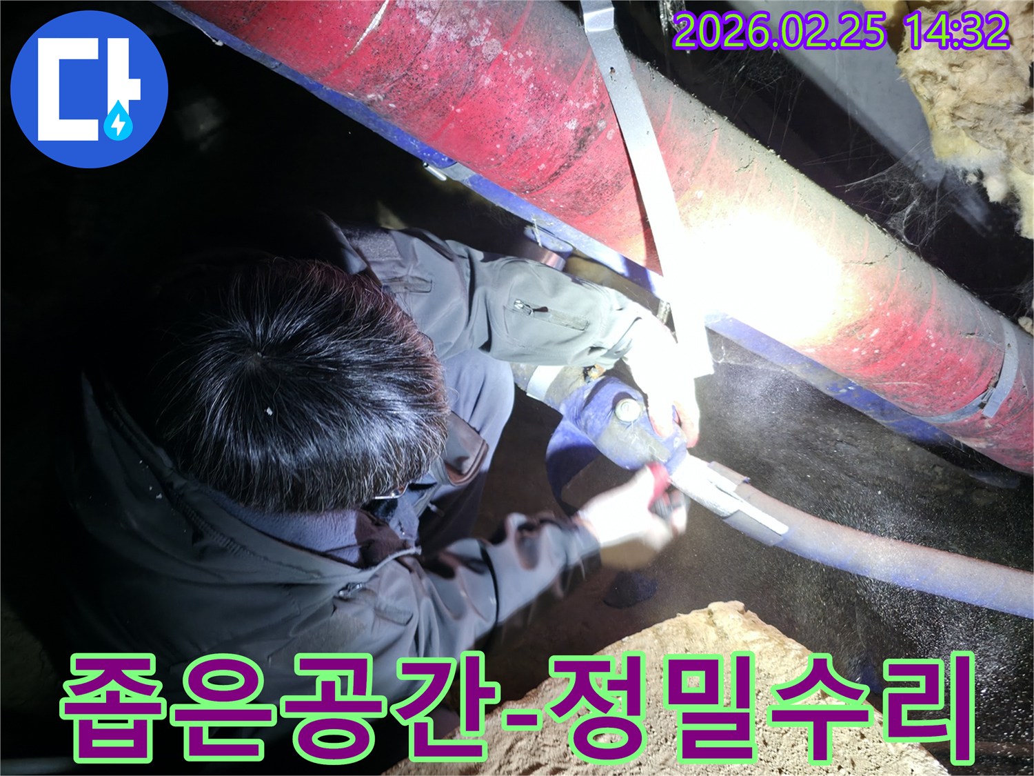전문 엔지니어가-어둡고 좁은 공간에서-작업등을 비추며-누수된 배관을-정밀하게 수리하고 있습니다