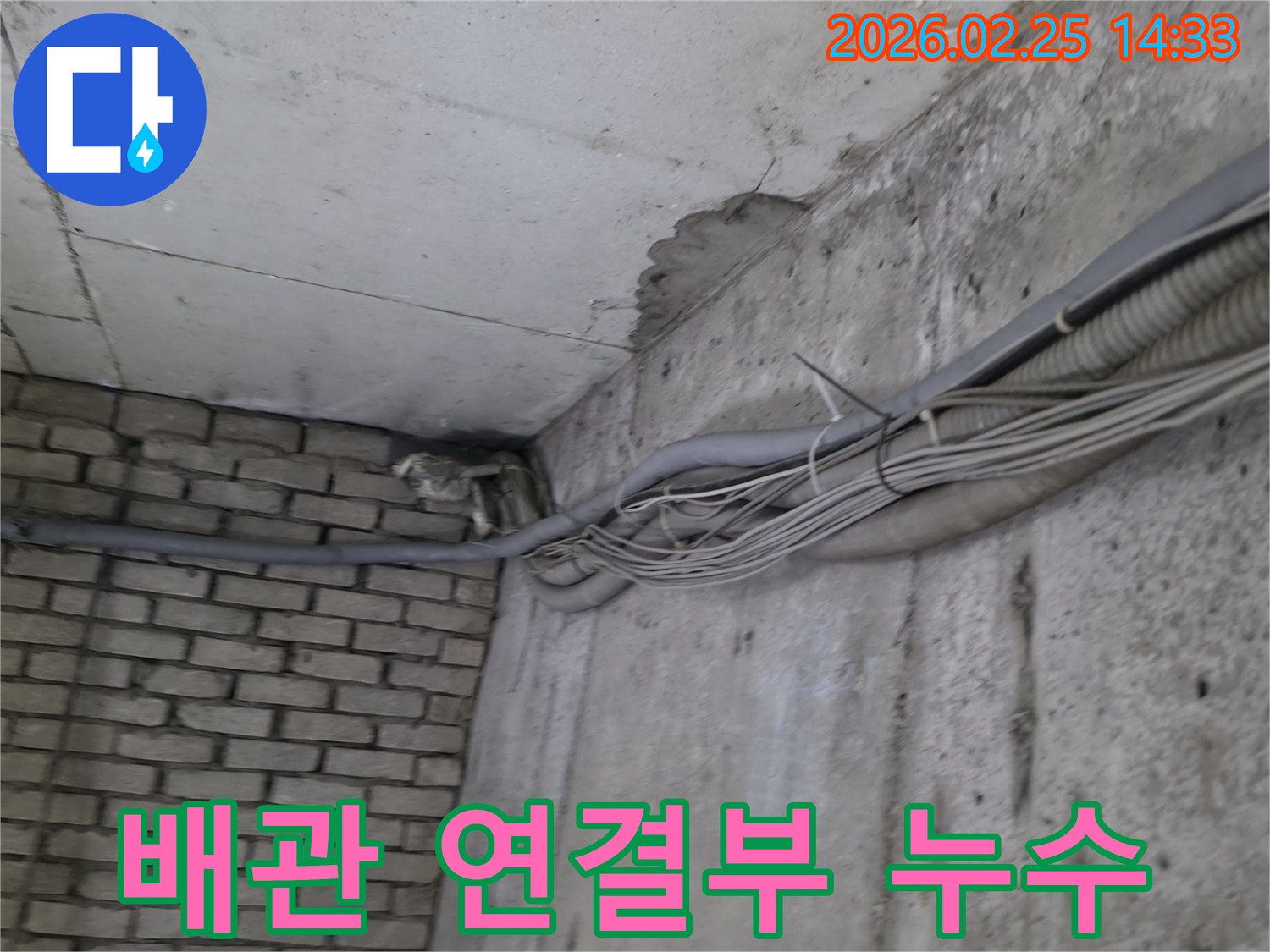 지하 벽면의-콘크리트와-벽돌 벽이 만나는-지점에서-발견된-오랜 누수로 인한-물자국과-주변의 복잡한 배관