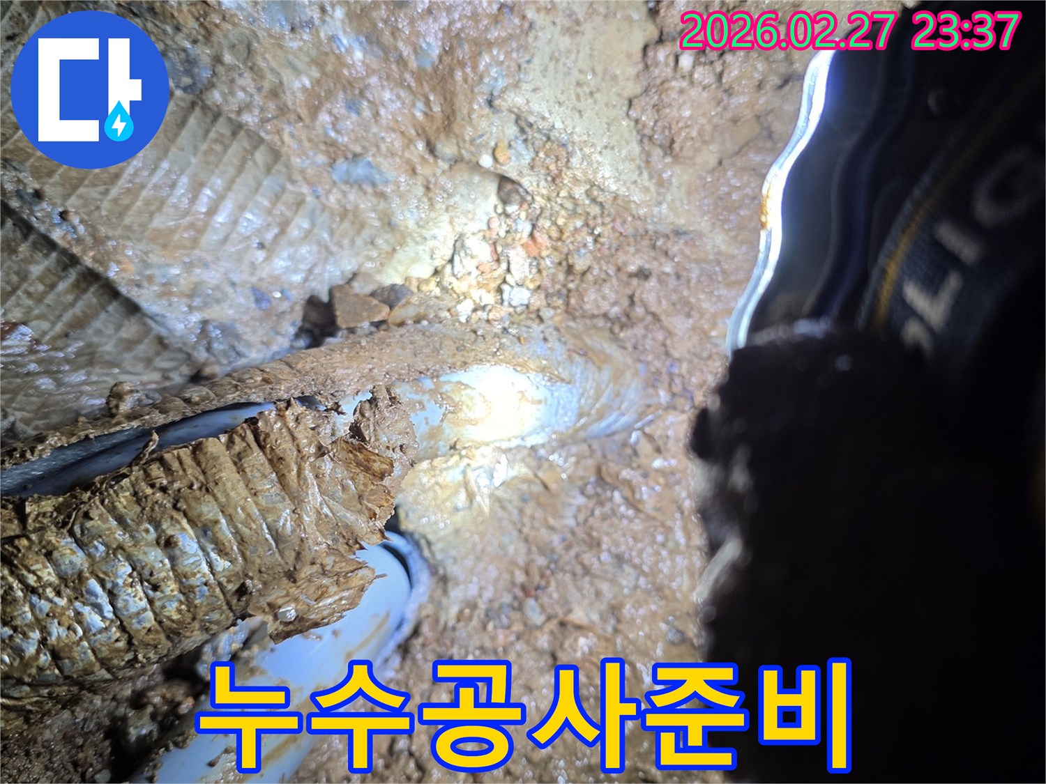 어두운-곳에서-작업등으로-비춰진-누수-발생-지점의-배관과-젖은-토양의-상세-사진