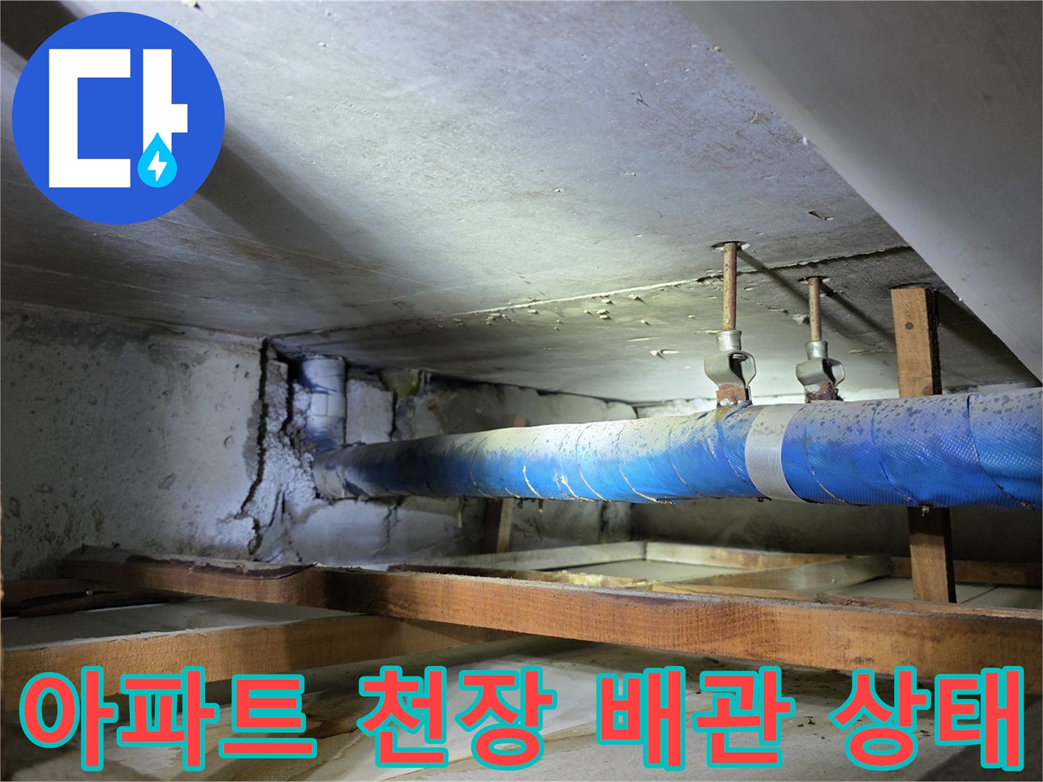 아파트 천장 내부의 파란색 보온재가 감겨진 배관과 목재 구조물 사진