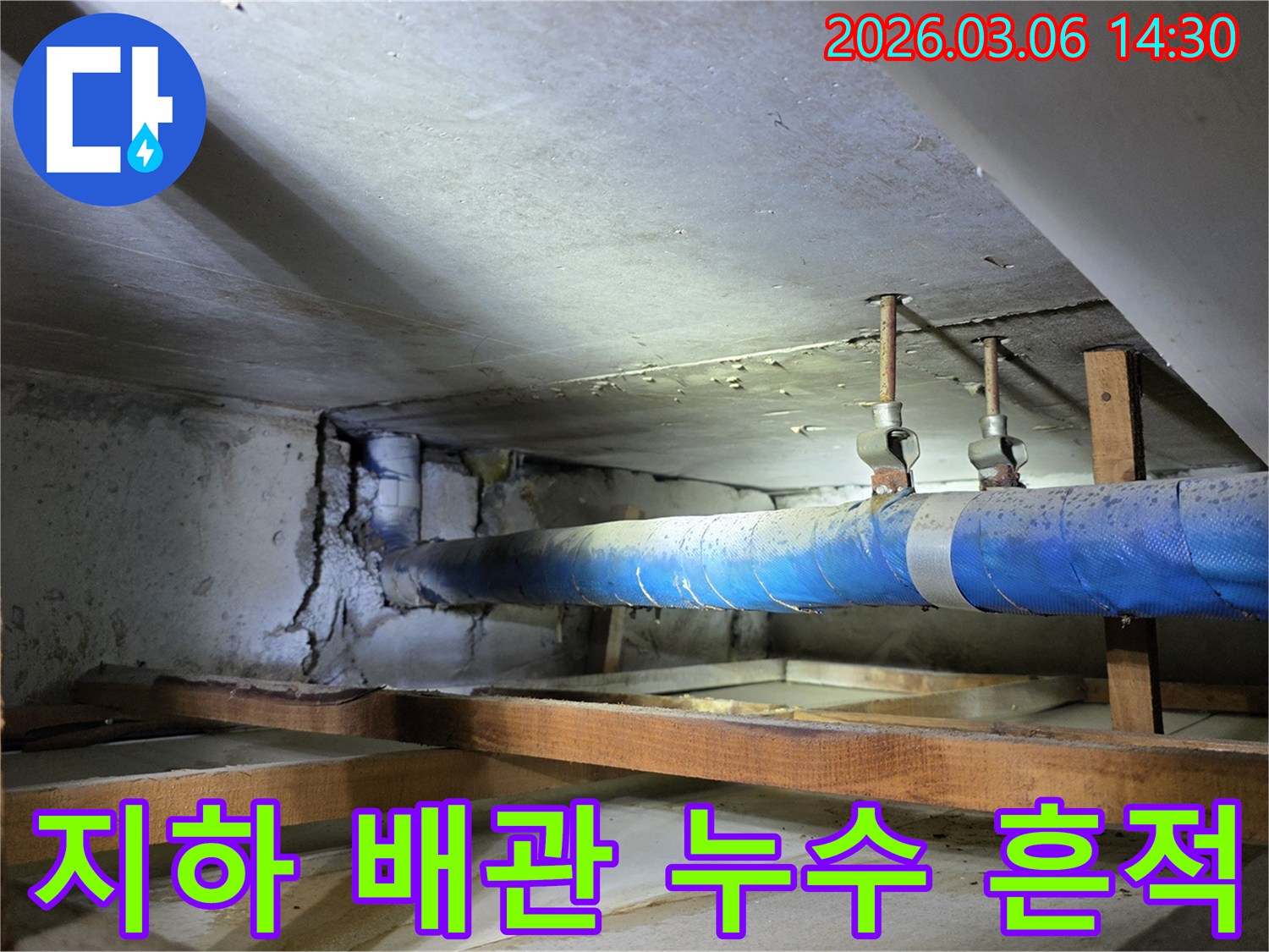 오래된 건물 지하에서 발견된-누수로 인해 손상된-콘크리트 벽면과-파란색 배관의 모습