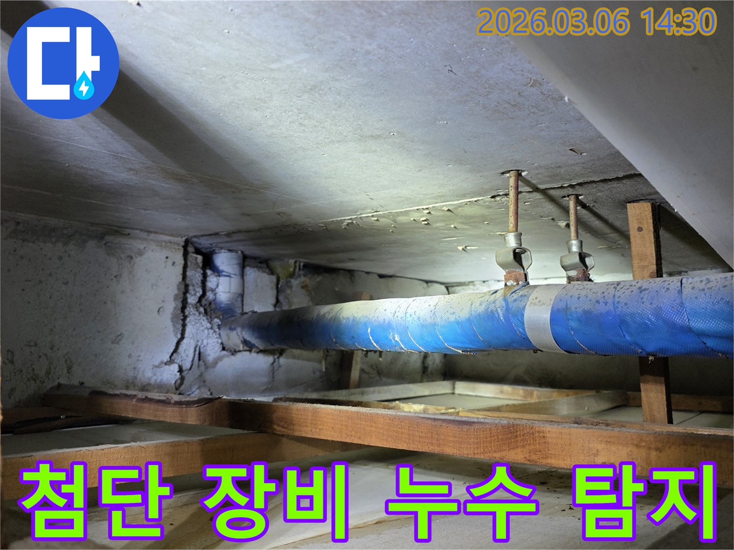 지하 공간의 파란색 배관과-손상된 콘크리트 벽면을-누수 엔지니어가-첨단 장비를 사용하여-정확하게 탐지하는 모습