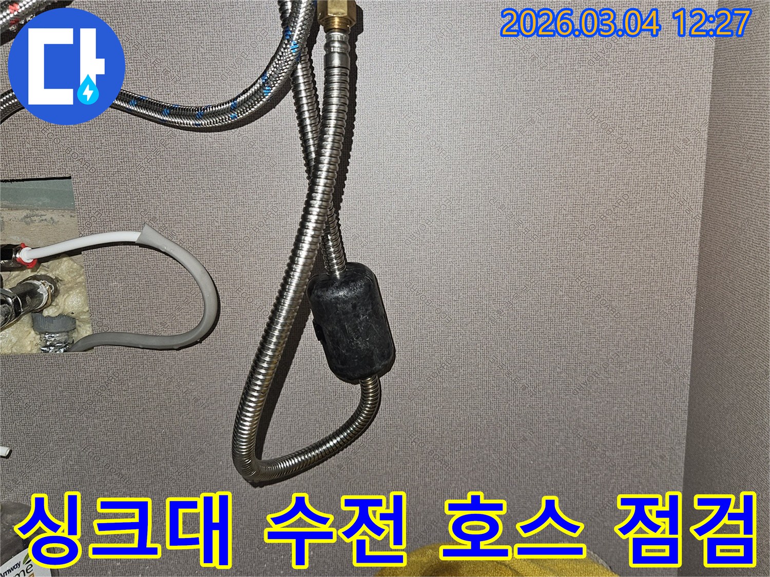싱크대 아래에 위치한-수전으로 연결되는 유연한 수도 호스와-그 주변의 배관 상태를 보여주는 사진