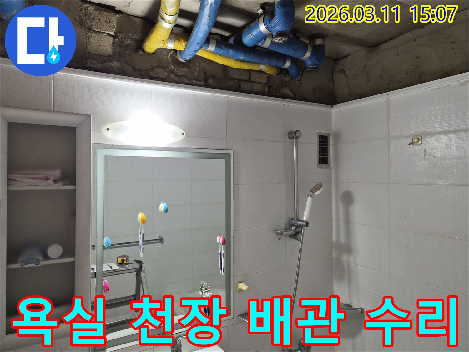 욕실 천장 속-파란색과 노란색 배관들이-수리 작업을 위해-노출된 모습