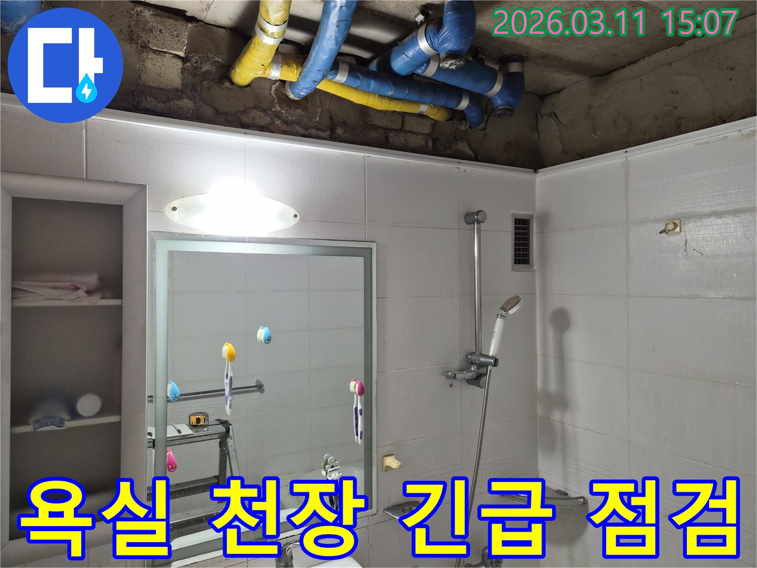 욕실 천장이 열려-파란색과 노란색 배관들이-긴급 누수 점검을 위해-노출된 현장 모습