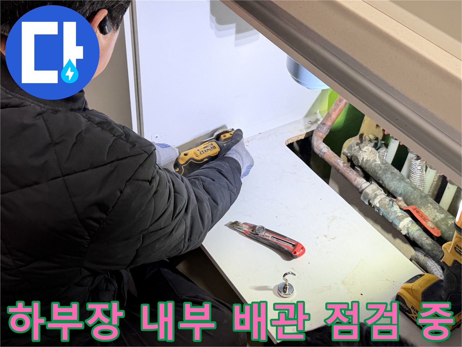 싱크대 하단 공간의 노후된 배관과 작업 도구들
