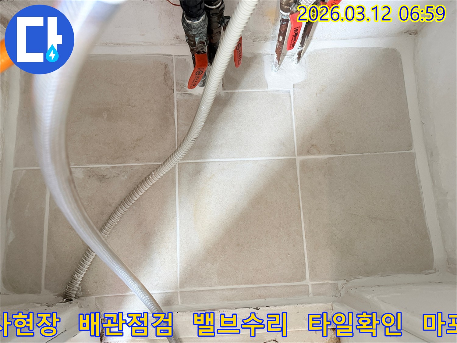 이 사진은-누수 엔지니어가-마포구의 한 현장에서-누수 공사 중-배관과-밸브-그리고-주변 타일의-상태를-점검하는-모습입니다