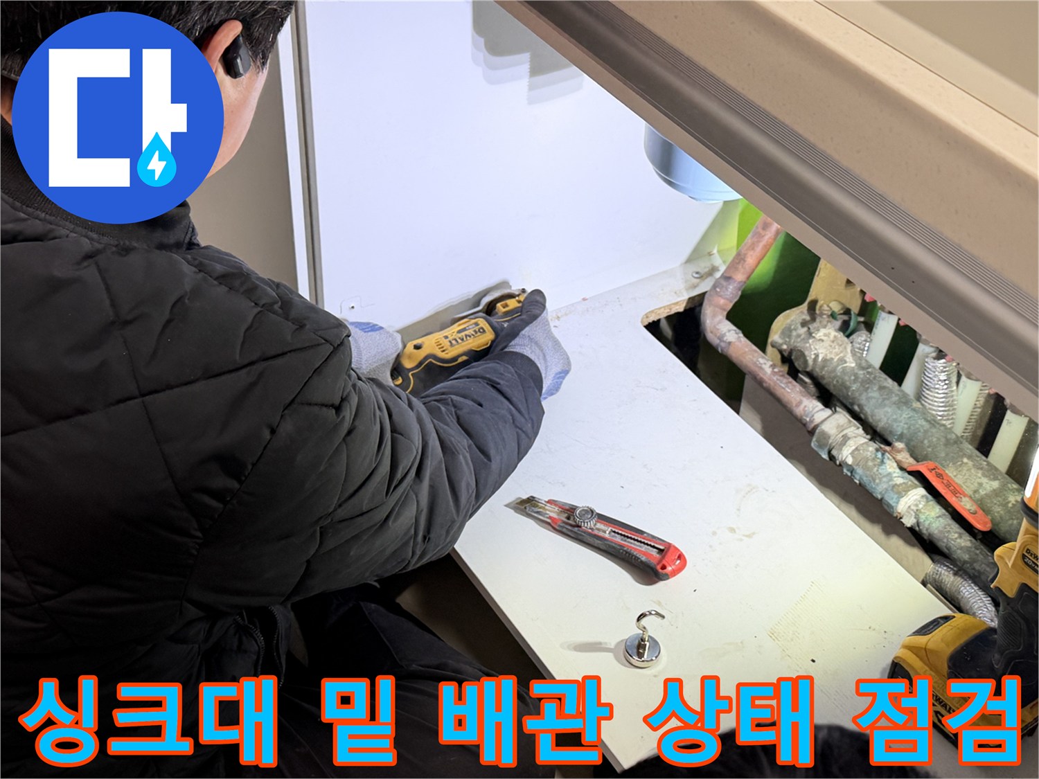 작업자가 싱크대 하부에서 배관을 살펴보는 장면