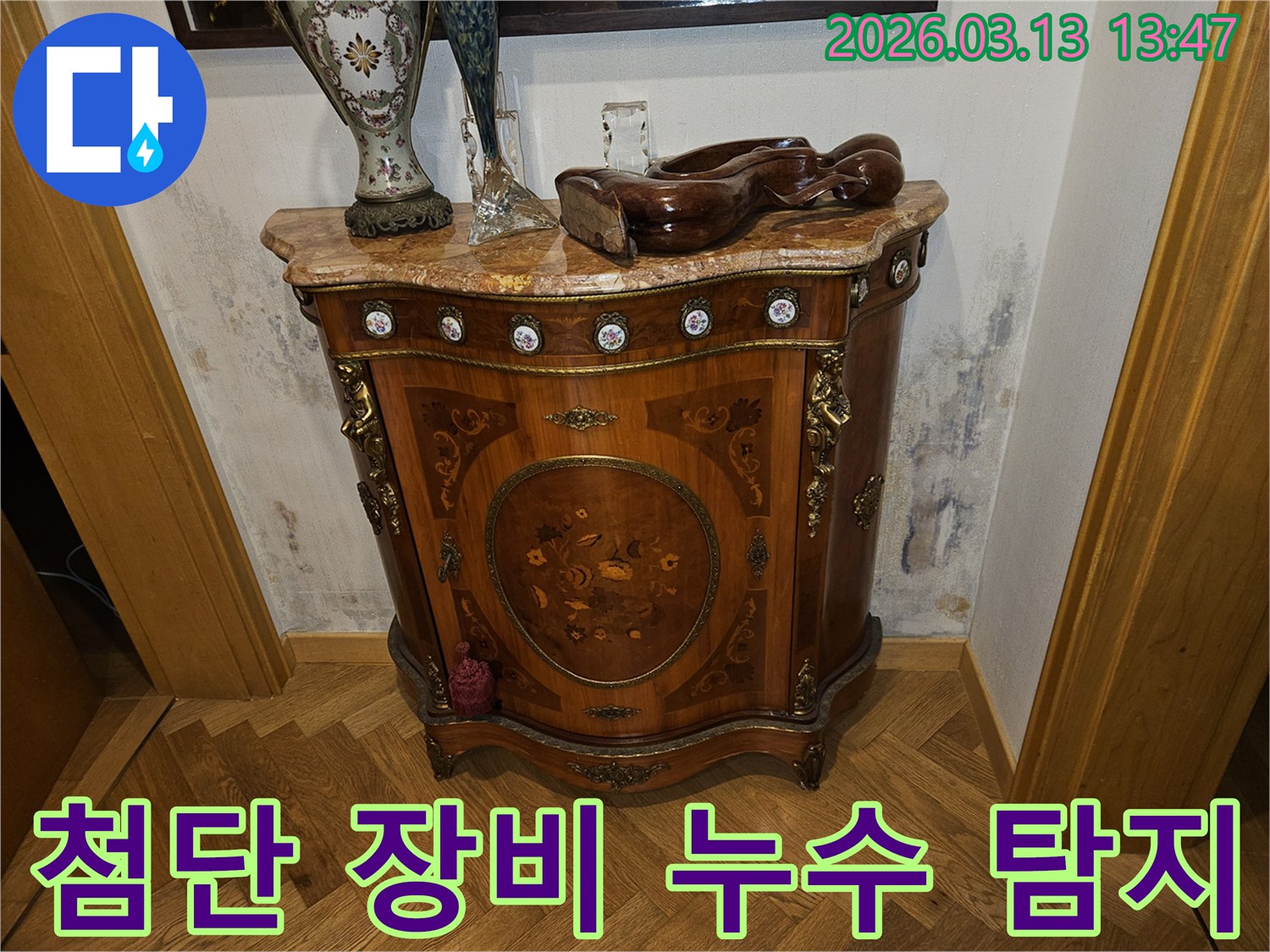 고급스러운 콘솔 가구 뒤-벽에 발생한-누수로 인한-벽지 변색과-곰팡이 흔적을 보여주는 사진