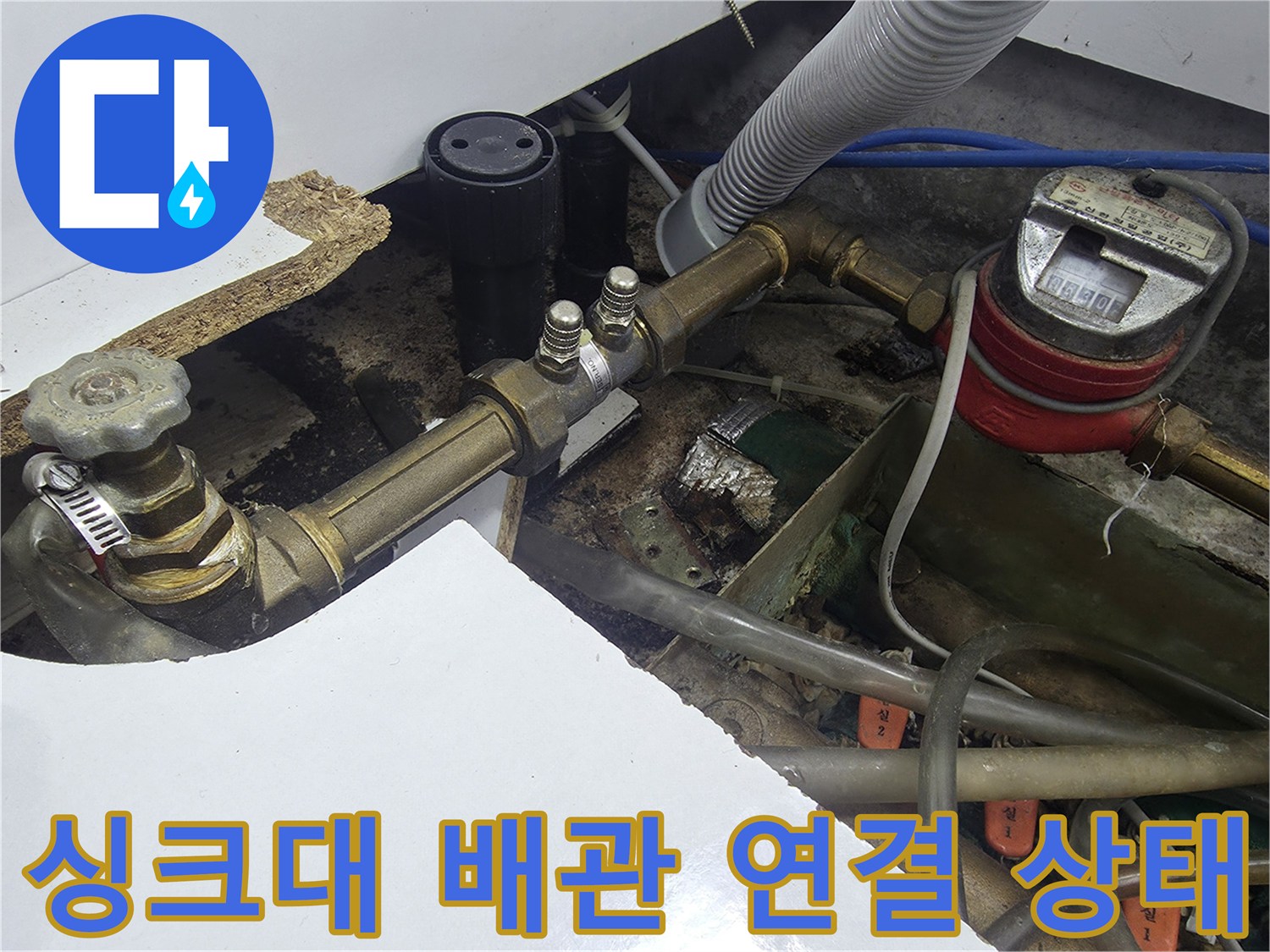 주방 싱크대 밑에 설치된 수도 계량기와 급수 배관