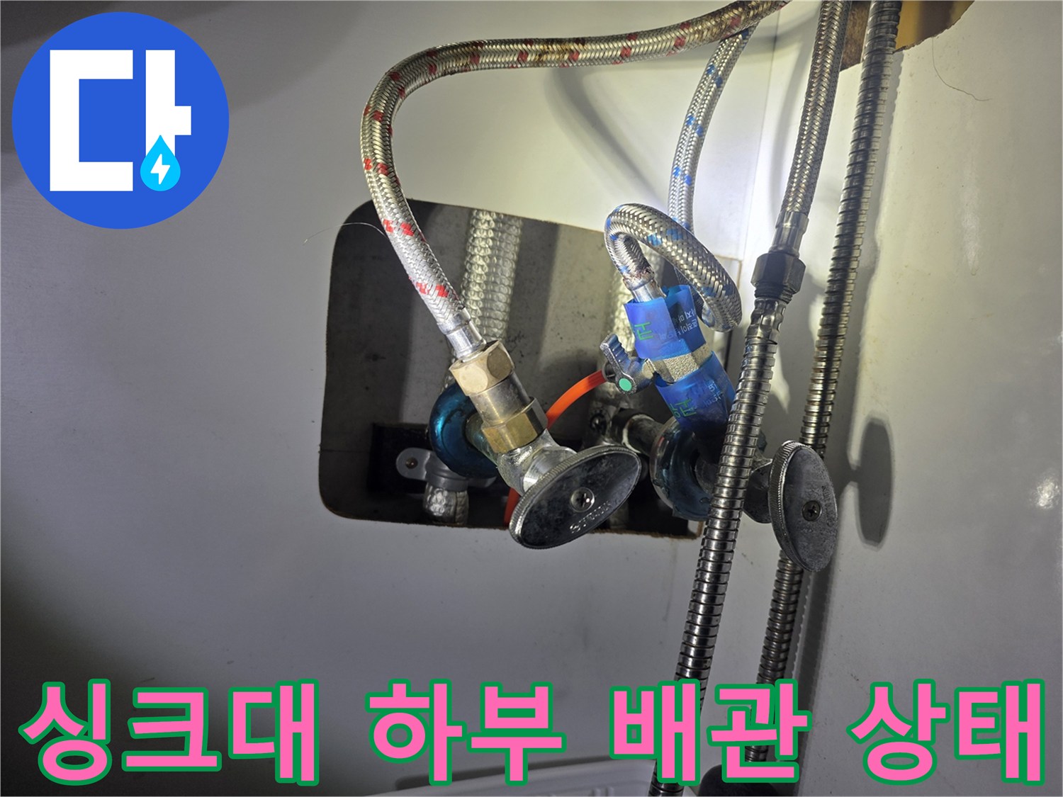 주방 싱크대 하부의 노후된 급수 호스와 밸브 연결 부위 모습