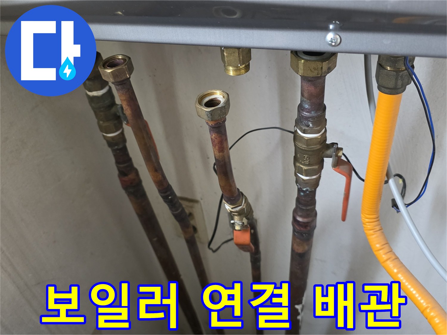 보일러 하단에 연결된 여러 개의 금속 및 플라스틱 배관 모습