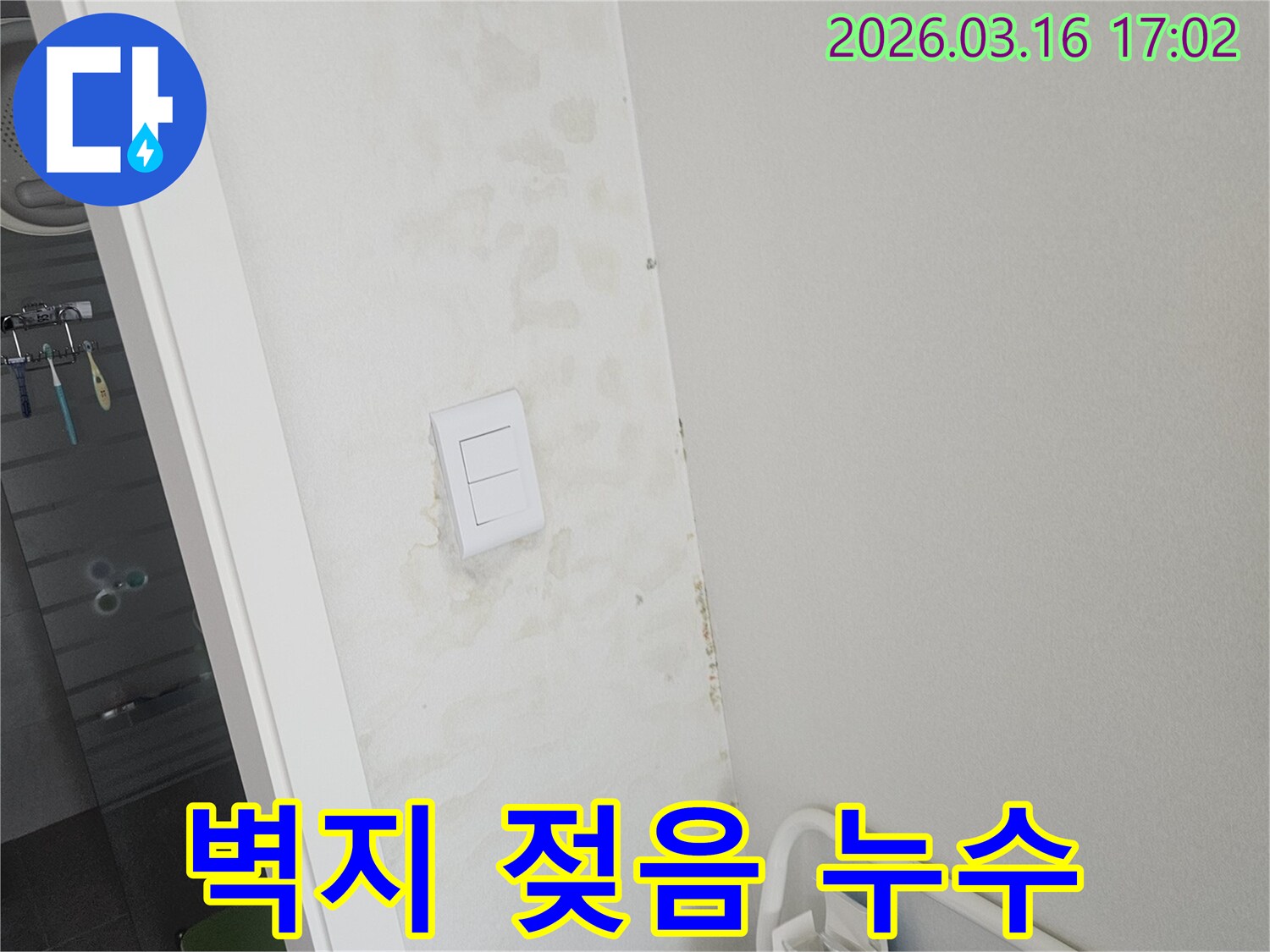 벽면의 스위치 주변으로 물이 스며들어 벽지가 젖고 변색된 모습-누수 의심 현장
