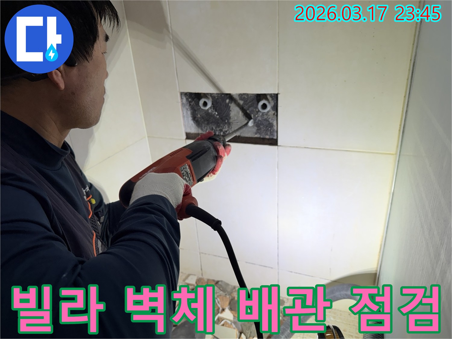 누수 공사 전문가가 빌라 욕실 벽면의 타일을 조심스럽게 파쇄하여-누수 원인을 찾기 위한 배관 상태 점검 작업을 진행하는 모습입니다.