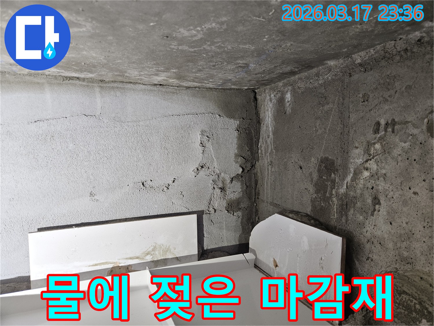 누수로 인해 바닥에 놓인 마감재가 물에 젖어 손상된 모습-내부 누수가 진행되고 있음을 보여줍니다.