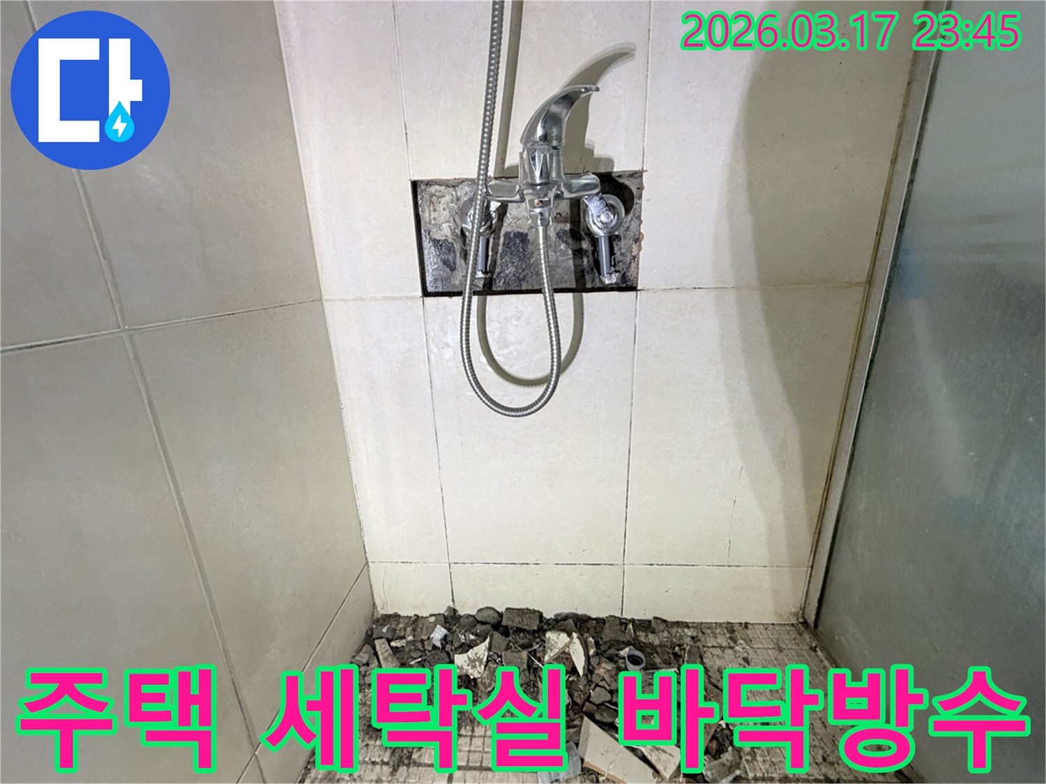 병점동 주택 세탁실에서-배수구 누수 배관 교체 및 바닥 방수를 위해-샤워 수전이 제거되고-바닥 타일이 파손된 채로-공사가 진행 중인 모습입니다.