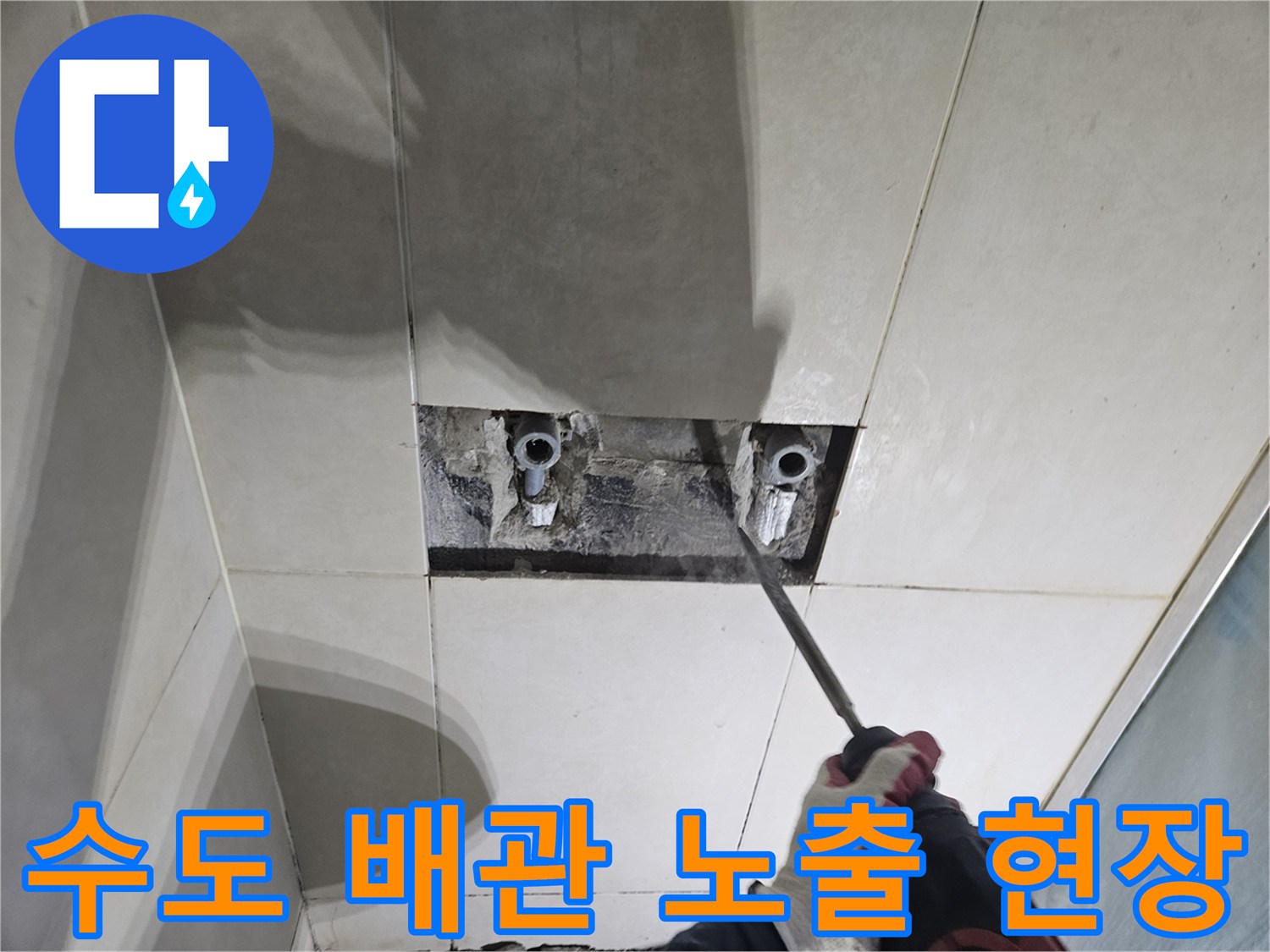 샤워 수전 뒤쪽의 손상된 배관을 확인하기 위한 타일 제거 작업