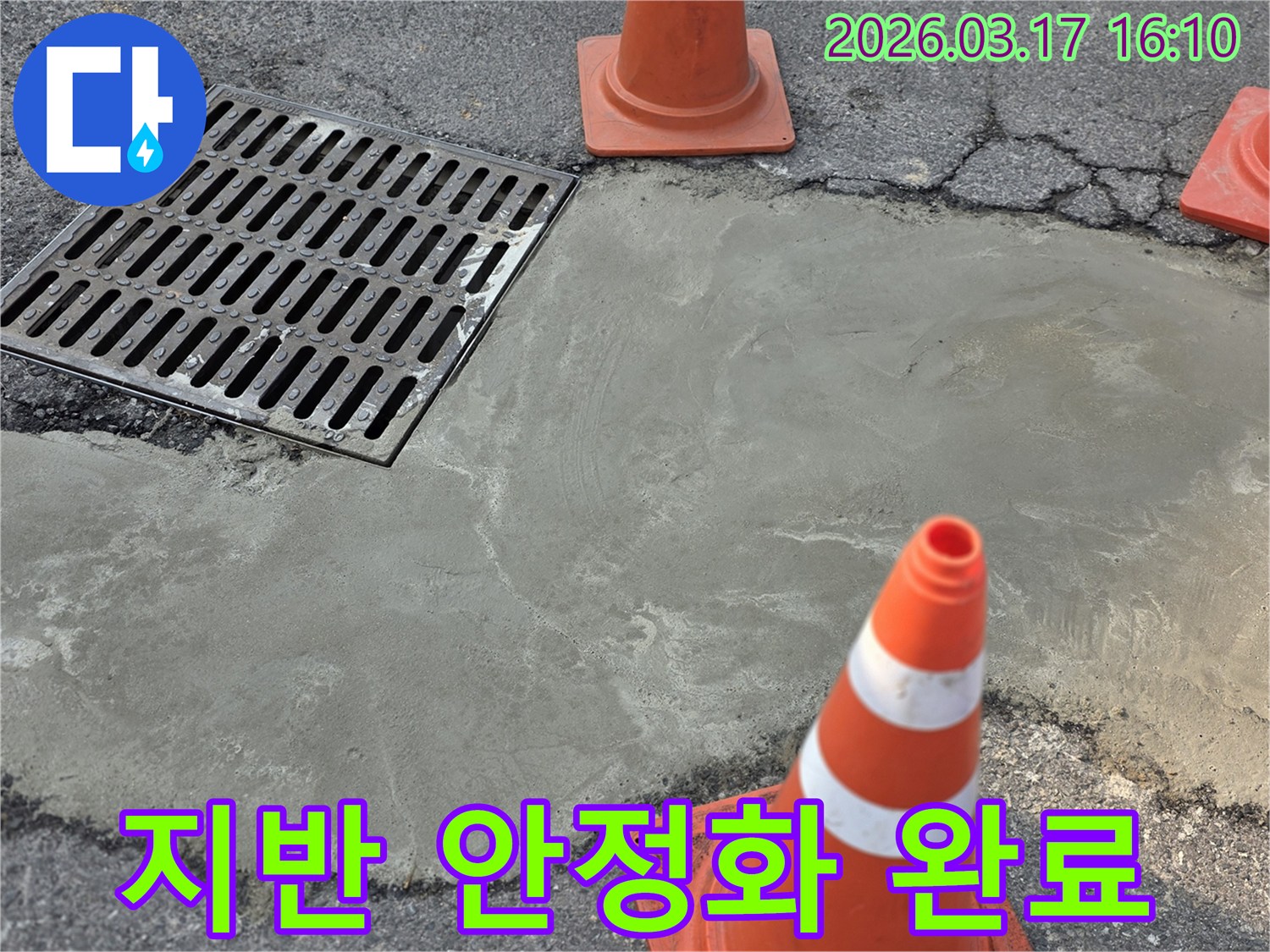 이 이미지는 양주 율정동의 외부 지반 침하로 인한 누수 문제를 해결하고-새로운 시멘트 마감으로 지반을 안정화한 현장을 보여주며-안전 콘이 설치되어 있습니다.