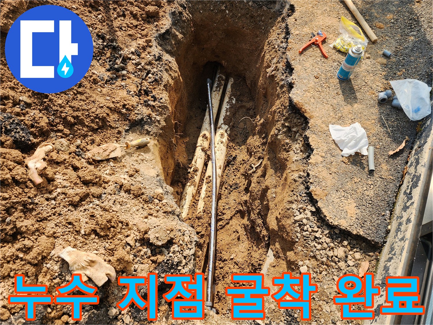 지면을 파헤쳐 드러난 상수도 배관과 작업 도구들
