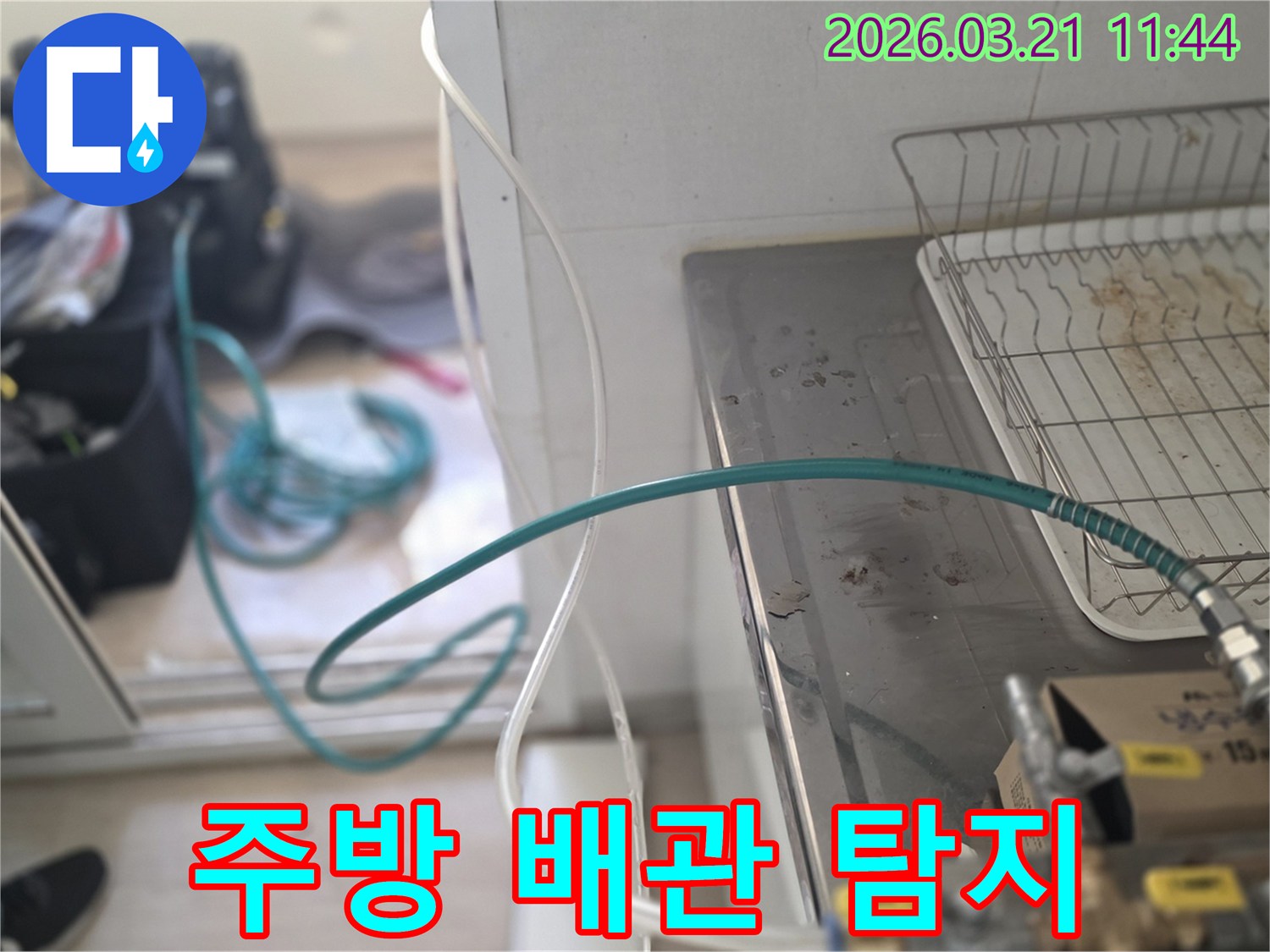 숙련된 누수 엔지니어가-주택 주방 싱크대 하부 배관에-누수탐지 장비를 연결하고 있습니다