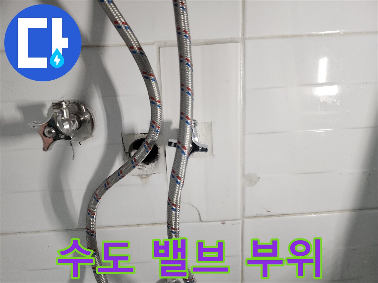 벽면 타일 안쪽에서 드러난 수도 연결 밸브와 샤워 호스