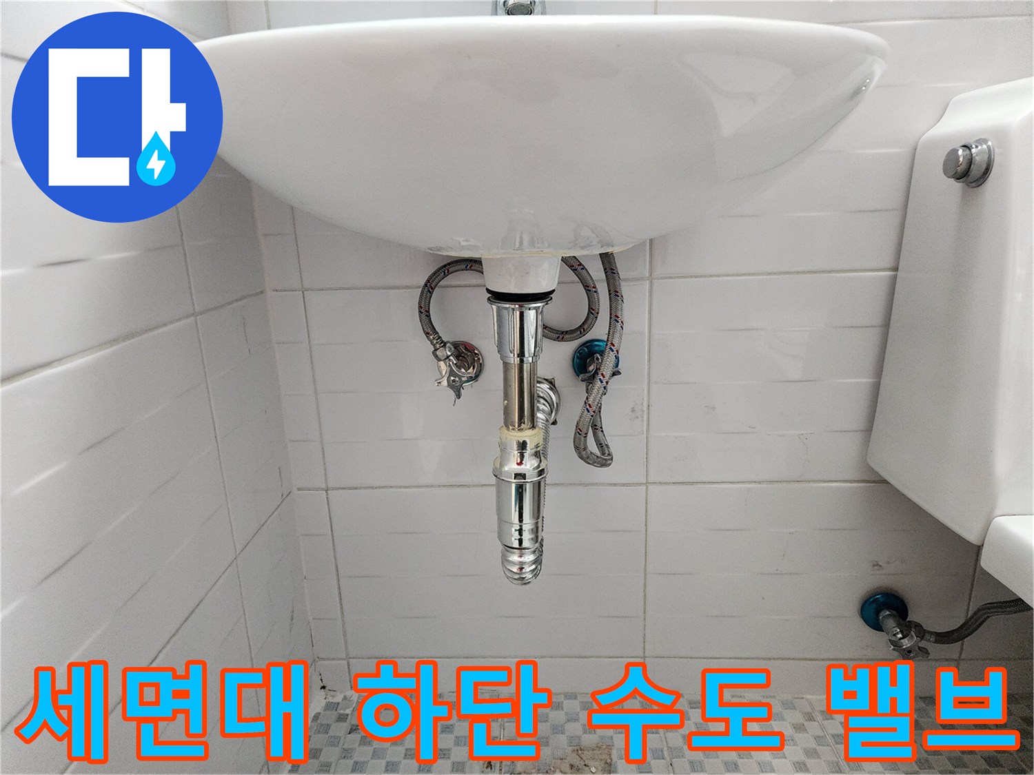 세면대 아래쪽 벽면에 설치된 수도 배관 연결 부위입니다.