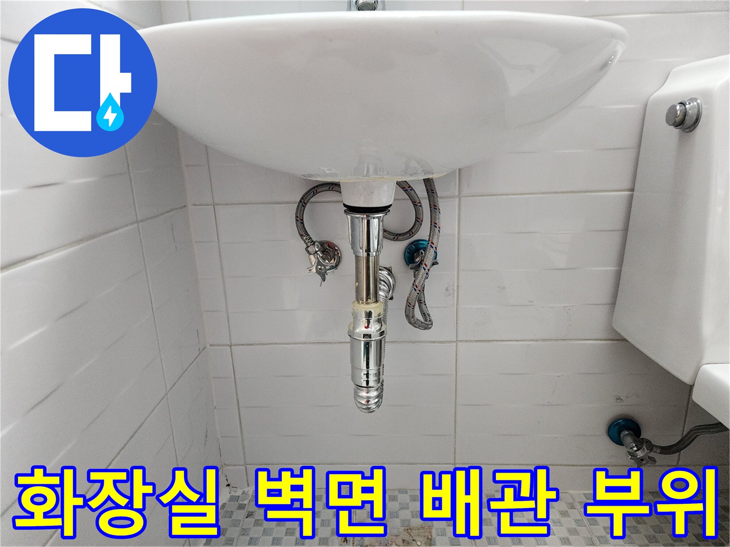 세면대 하단 타일벽에 설치된 급수 밸브와 호스
