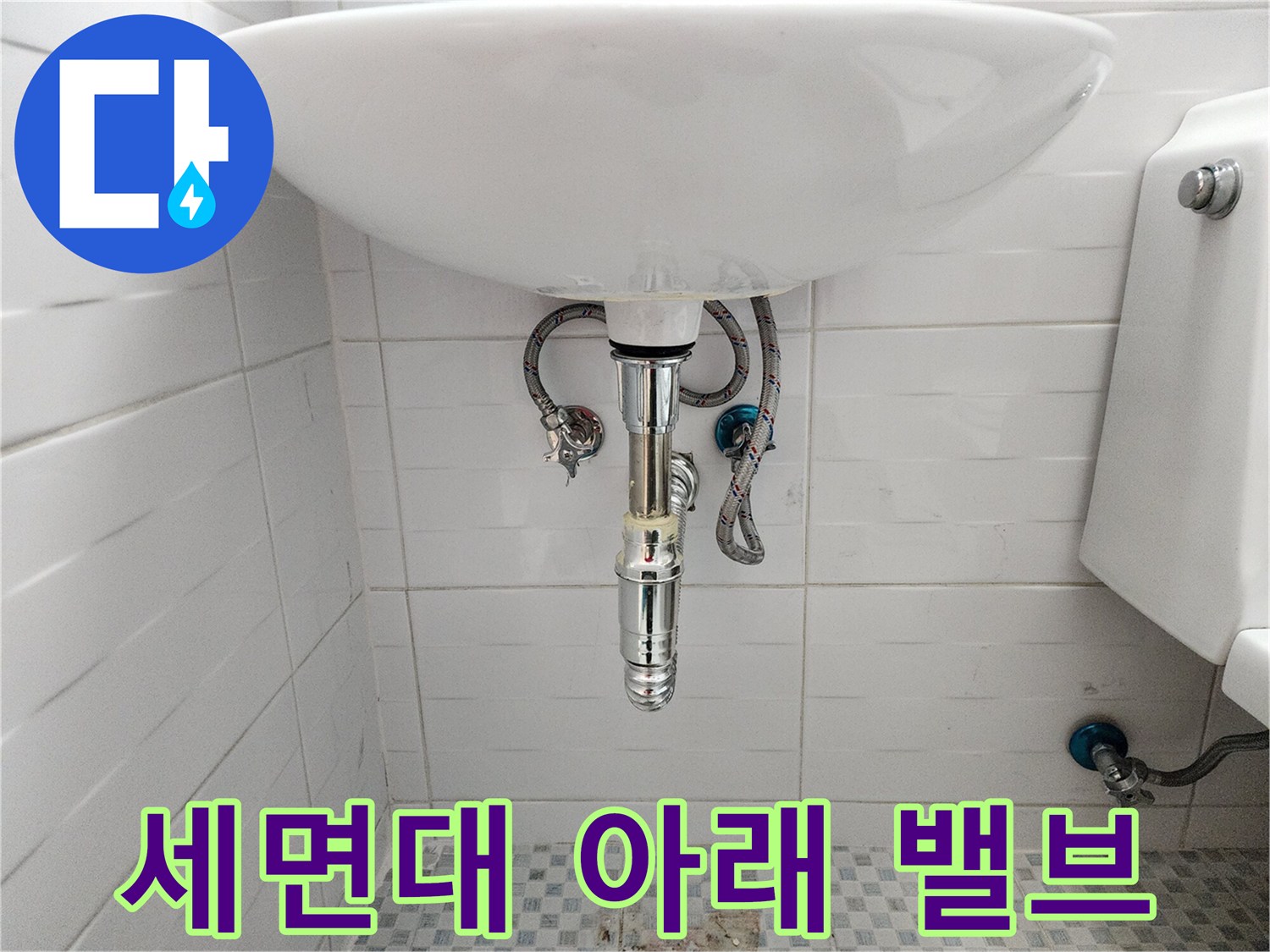 세면대 하부의 은색 금속 밸브와 급수 호스 연결 상태